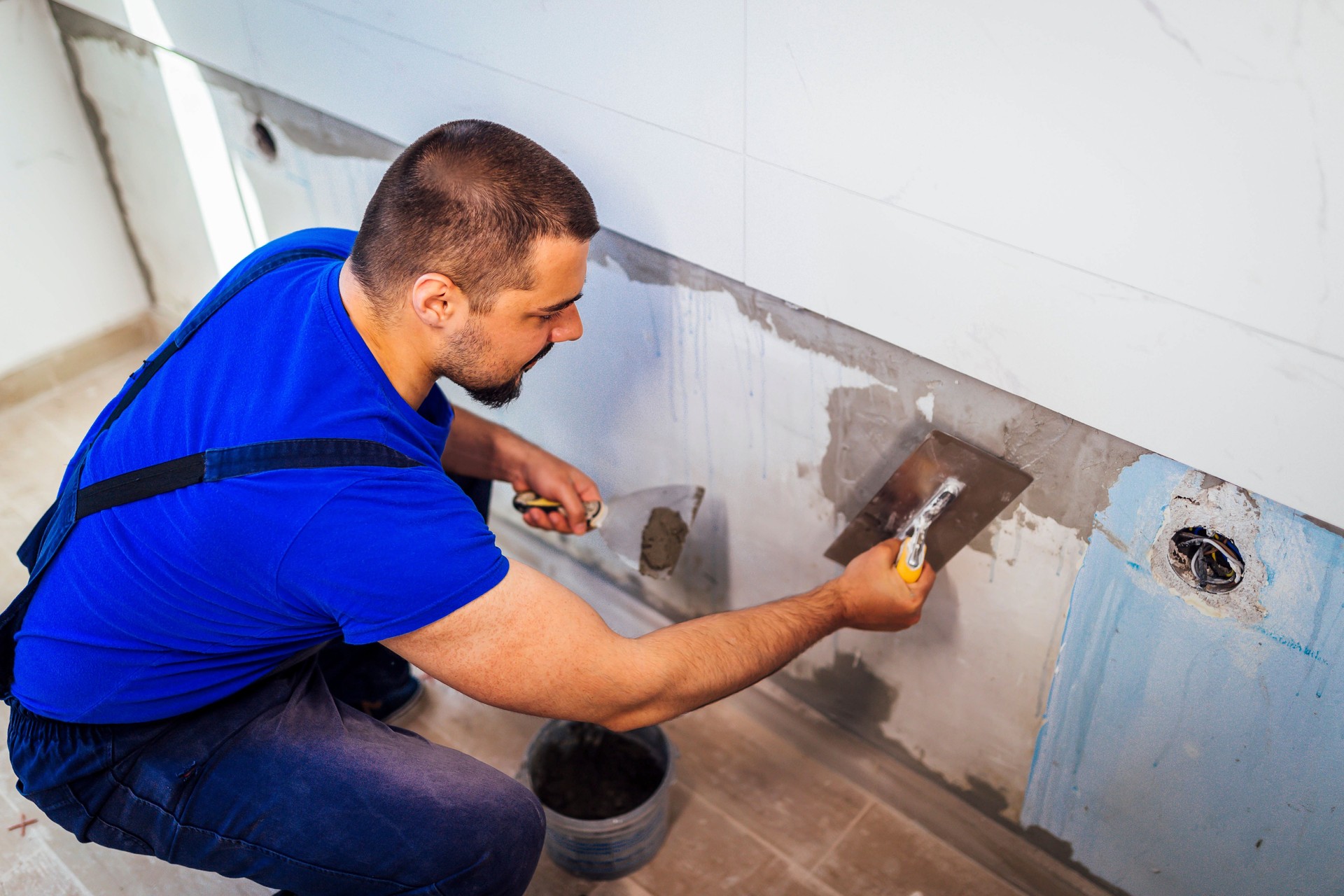 Tiler está aplicando adhesivo a la pared de la cocina